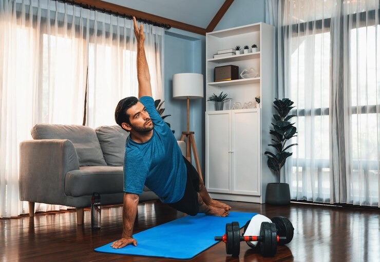 Homem praticando exercício físico em casa, realizando uma postura de alongamento, destacando a importância da atividade física na prevenção do câncer. 