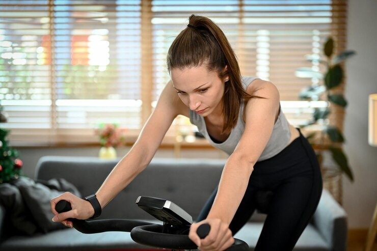 Mulher praticando exercício aeróbico em uma bicicleta ergométrica na sala de casa.  