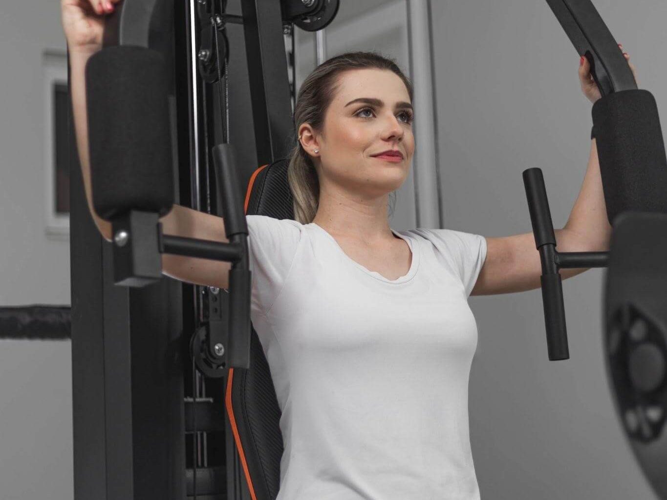 Mulher treinando peito em uma estação de musculação Athletic 