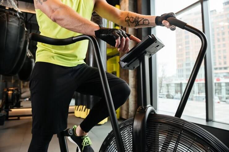 Homem em uma academia treinando em uma air bike.