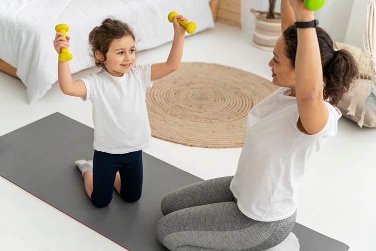 Mãe e filho pequena exercitando juntas com kit de halteres.