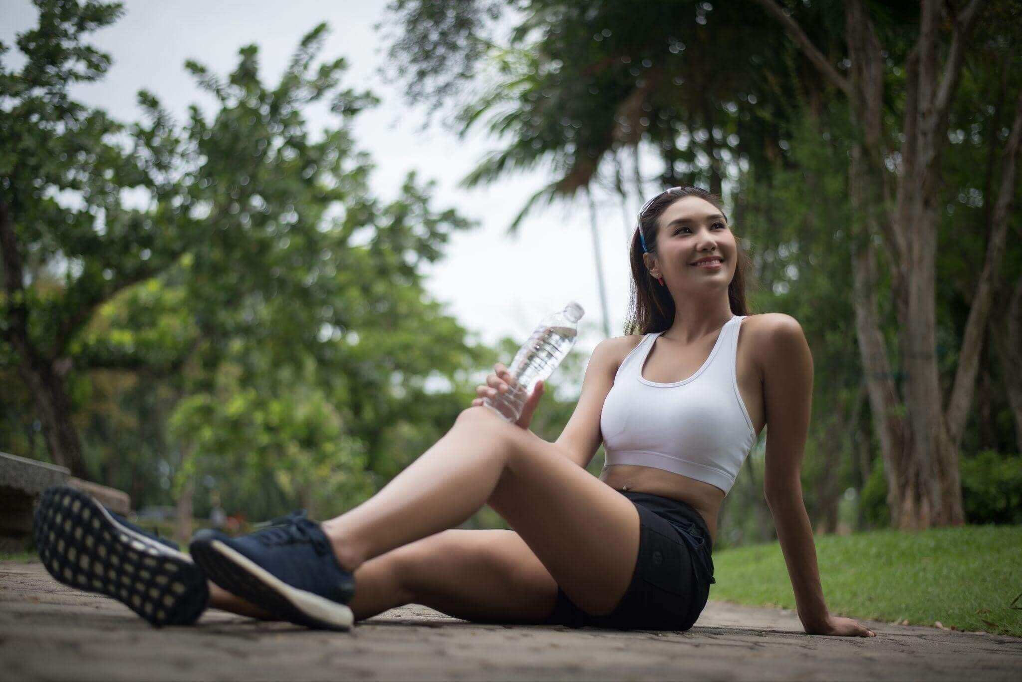 Mulher descansando após seu treino em praça.