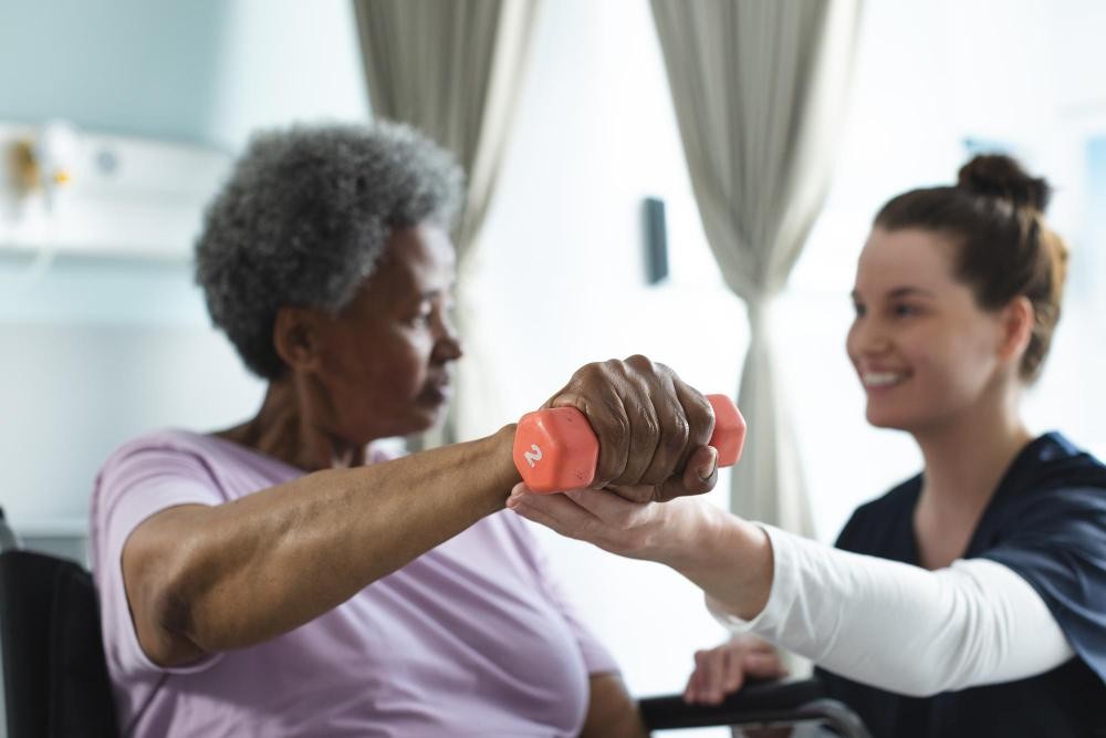 Mulher idosa em uma série de exercícios físicos para ajudar na luta contra o Parkinson acompanhada por uma profissional. 